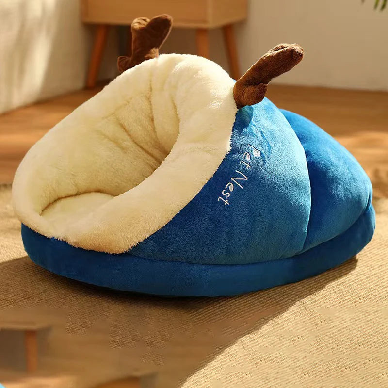 Panier pour chien en forme de nid de couleur bleu et blanc avec des oreilles brune. Le panier chien est posé dans un salon de couleur claire avec en fond un meuble en bois. Image produit Boutiquechien