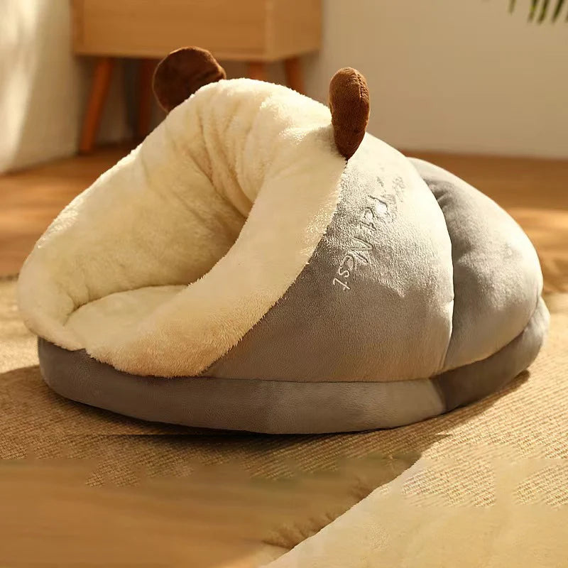 Panier pour chien en forme de nid de couleur gris et blanc avec des oreilles brune. Le panier chien est posé dans un salon de couleur claire avec en fond un meuble en bois. Image produit Boutiquechien