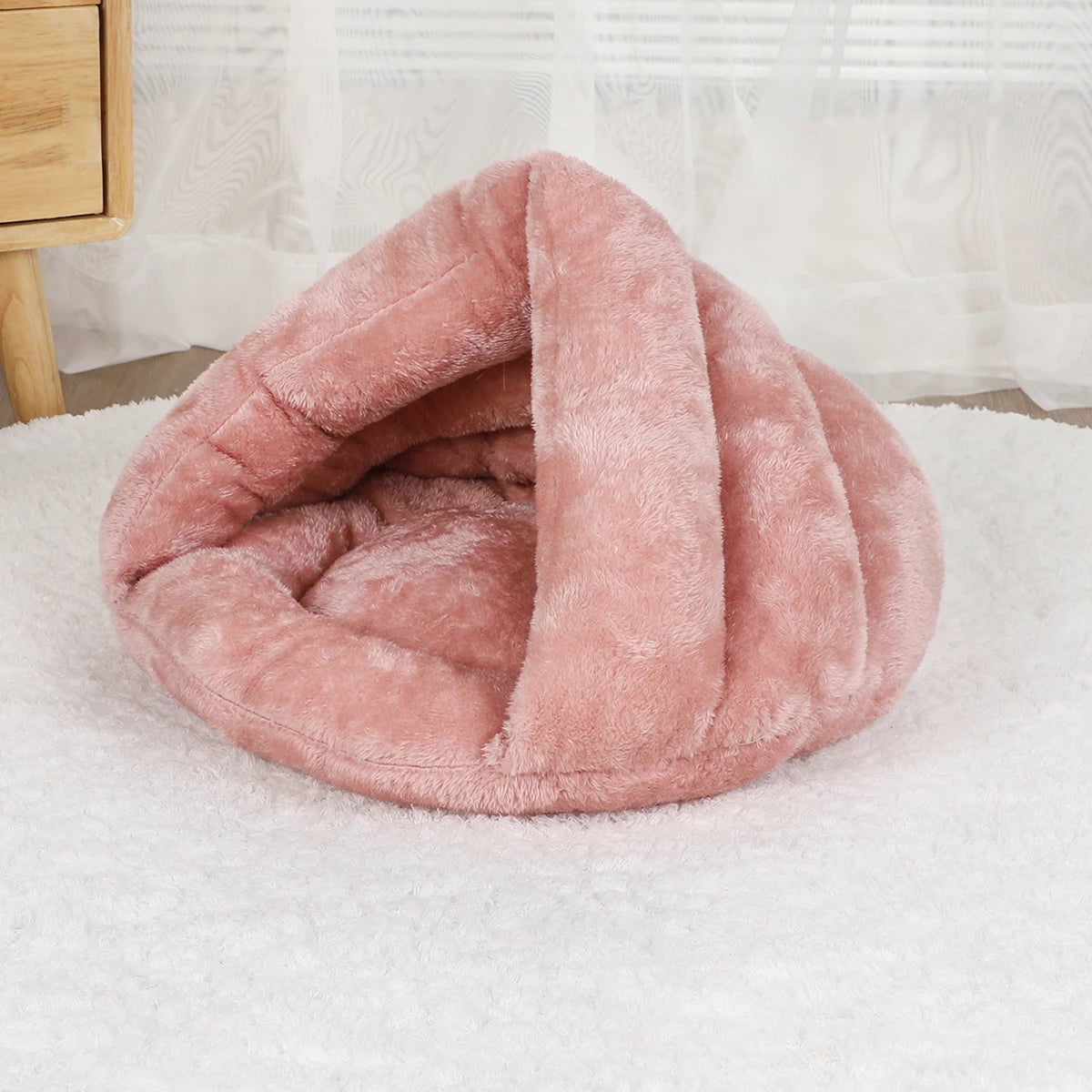 Panier pour chien de couleur rose en forme de nid posé dans le salon. Le produit est mis en valeur dans un salon de couleur claire. Image produit Boutiquechien