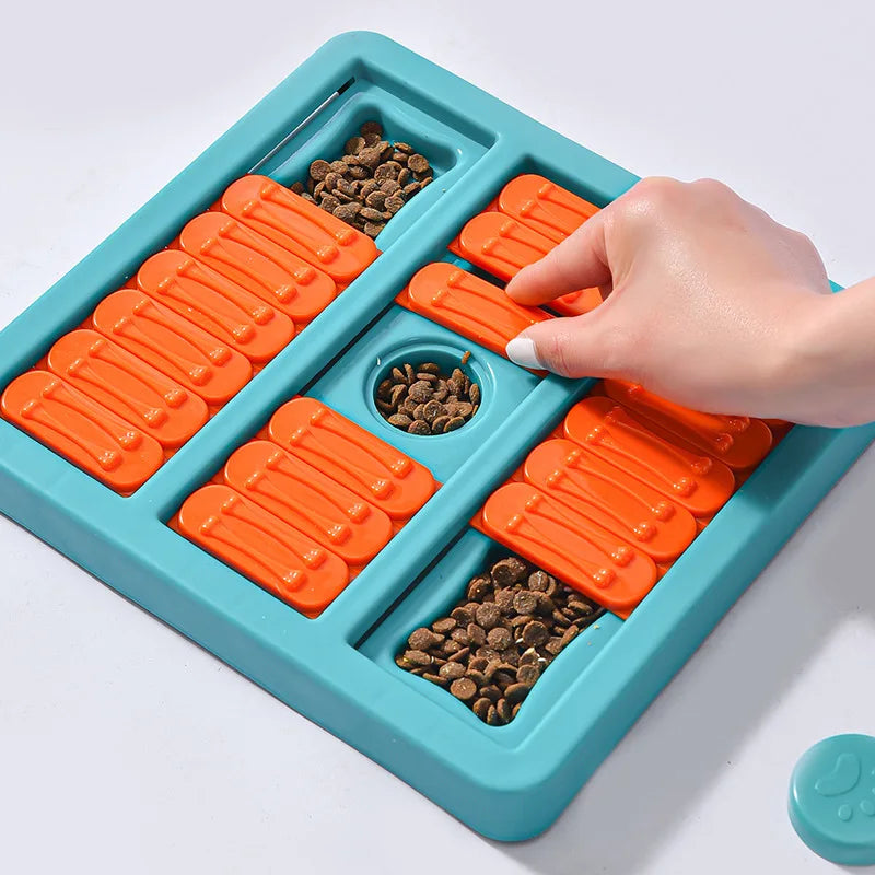 Puzzle pour les chiens de couleur bleu et orange avec des croquettes cachés dedans. Une main blanche touche les cachette du puzzle. Image produit Boutiquechien