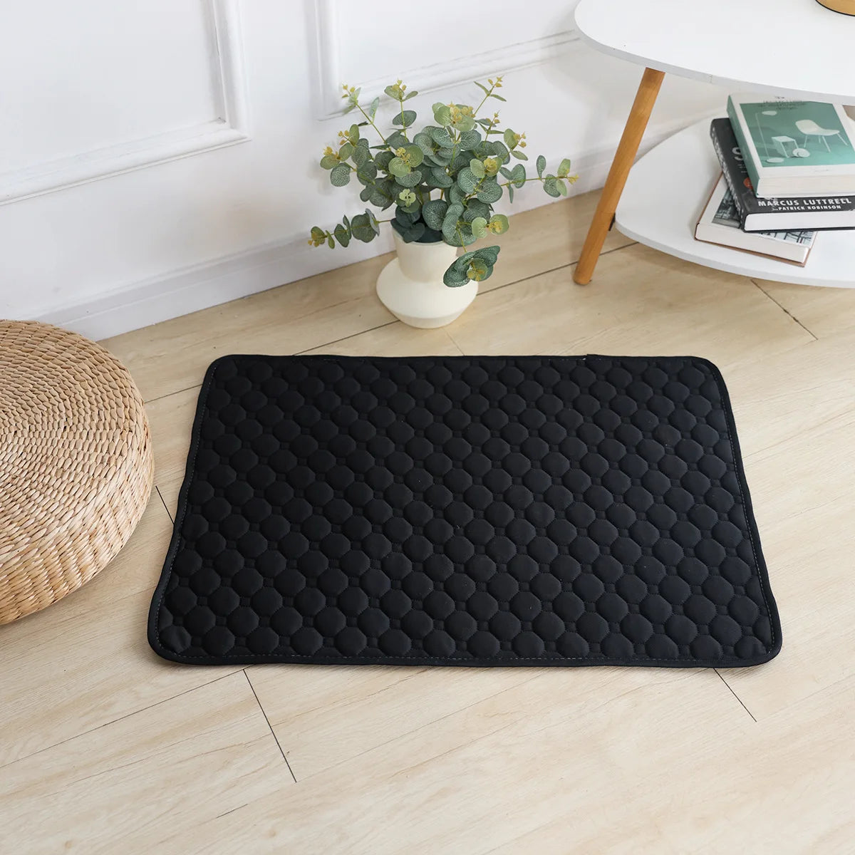 Tapis chien de couleur noir posé sur un sol de couleur claire. Le tapis chien absorbant est parfait pour les chiens. Le tapis est posé près d'une nappe blanche et d'une plante verte. Image produit Boutiuqechien