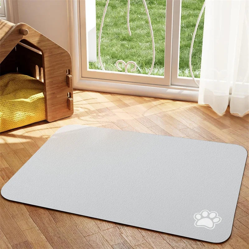 Tapis chien de couleur blanc foncé avec une patte de couleur blanche sur le tapis pour gamelle de chien. Le tapis à gamelle pour chien est posé dans un salon avec sur le côté une niche en bois. Image produit Boutiquechien