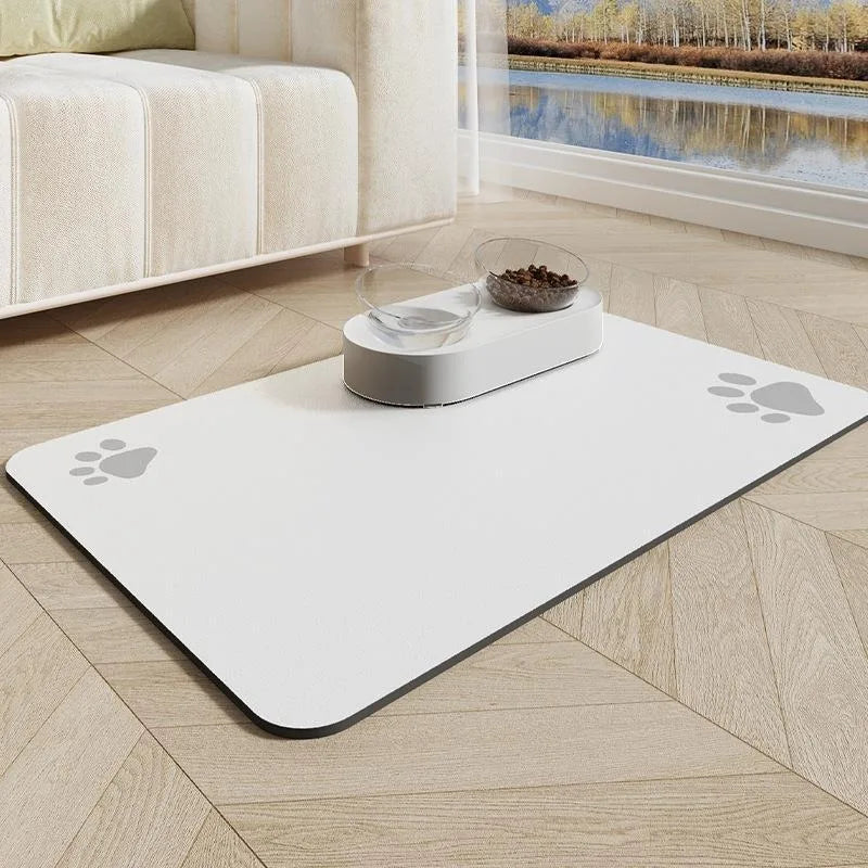 Tapis gamelle pour chien de couleur blanc avec des pattes grise. Le tapis chien est posé dans un salon de couleur claire avec en fond un canapé blanc et un ruisseau. Image produit Boutiquechien