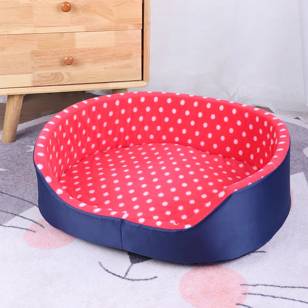 Tout petit panier pour chien de couleur rouge avec des pois blanc. En fond il y a un meuble en bois avec en dessous un tapis en forme de chat