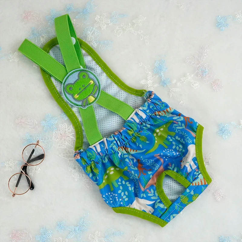 Couche à bretelle pour chien de couleur bleu claire avec des formes de Dino. Le produit est posé dans un fond blanc. Image produit Boutiquechien