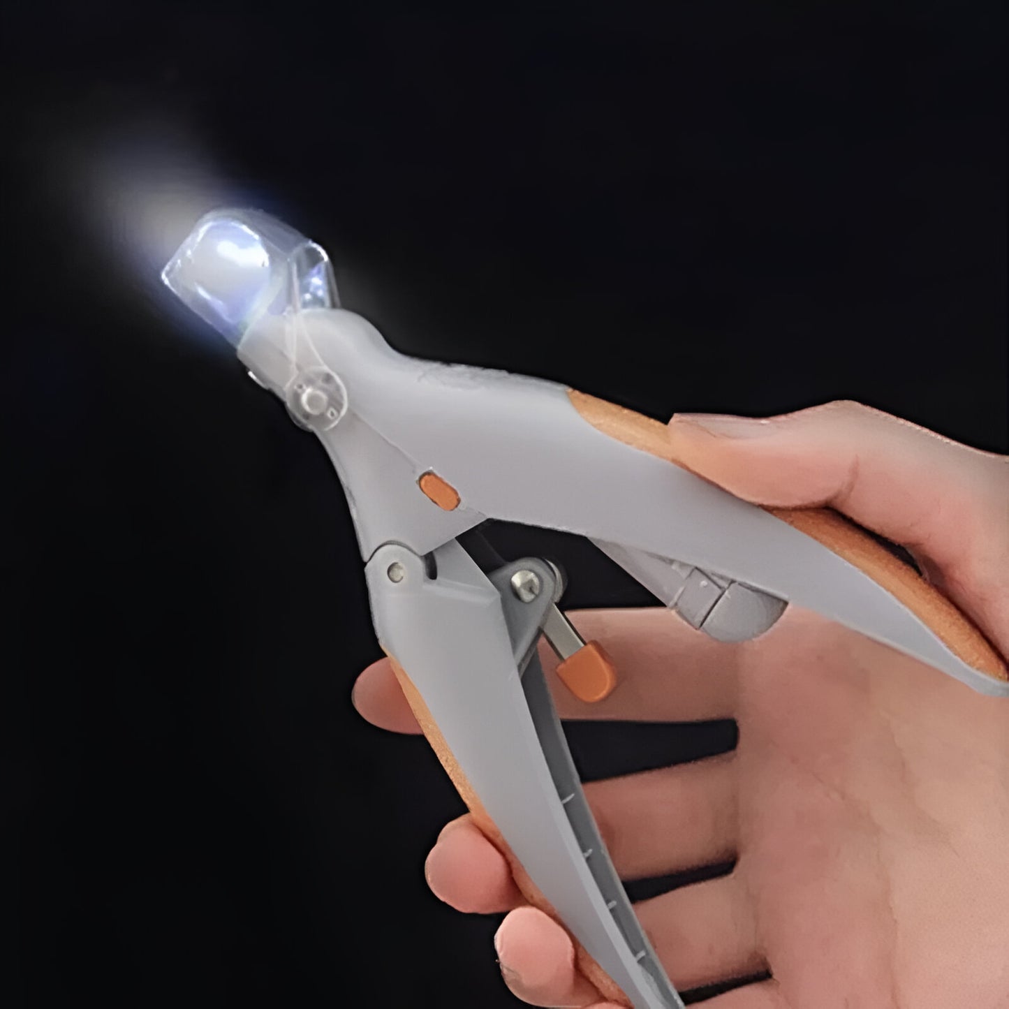 Led intégré au coupe ongle pour chien de couleur orange et gris maintenu par une main. Image produit Boutiquechien