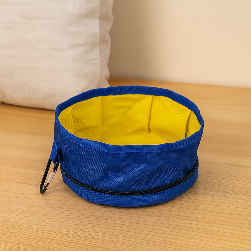 gamelle pour chien pliable de couleur bleu et jaune sur un sol en parquet avec en fond un coussin blanc. image produit Boutiquechien