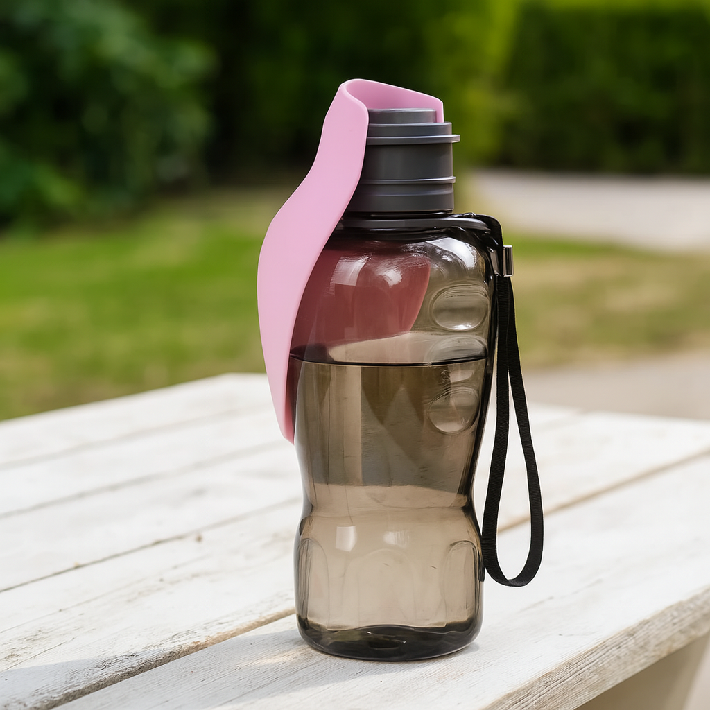 gourde d'eau pour chien de couleur Rose et noir posé sur une table en bois dans un parc verdoyant. Image produit Boutiquechien