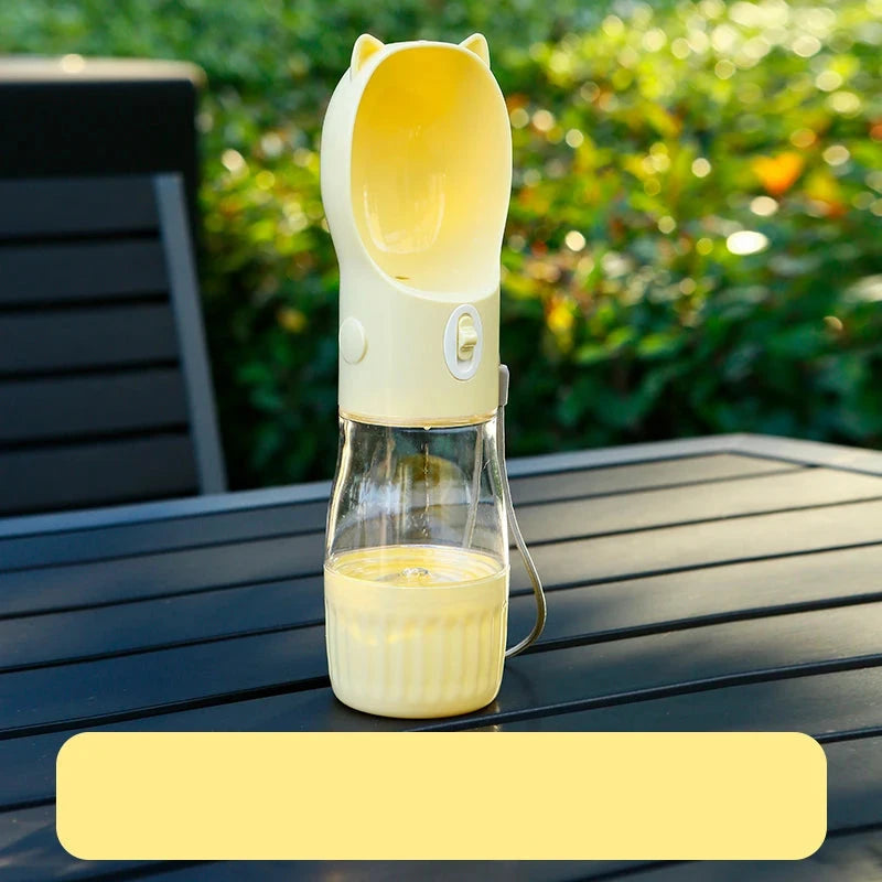 Gourde jaune d'eau et nourriture posé sur une table de jardin de couleur noir avec en fond une haie verte. Image produit Boutiquechien