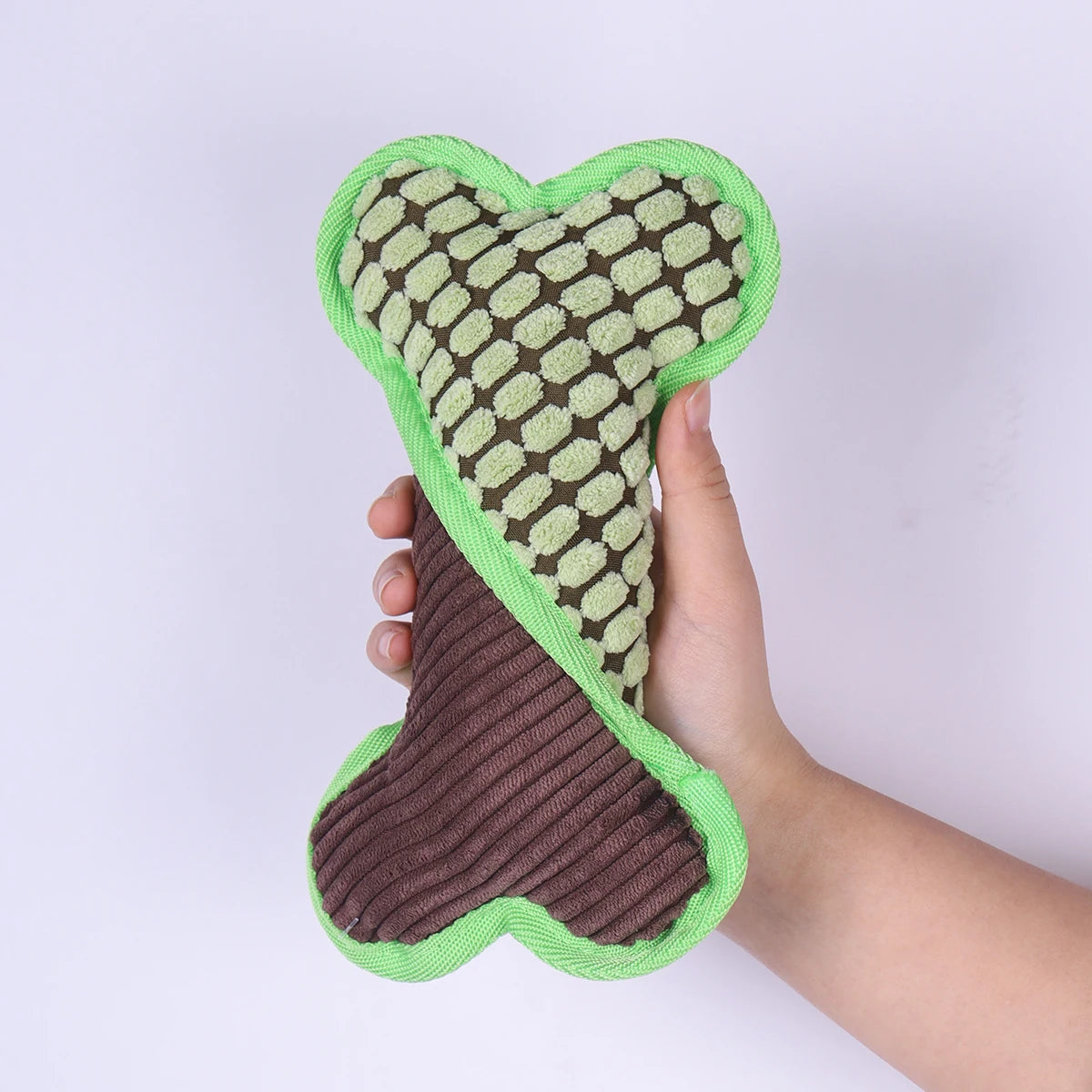 os chien vert et brun doux et moelleux pour chien. L'os chien est maintenu par une main. Image produit Boutiquechien