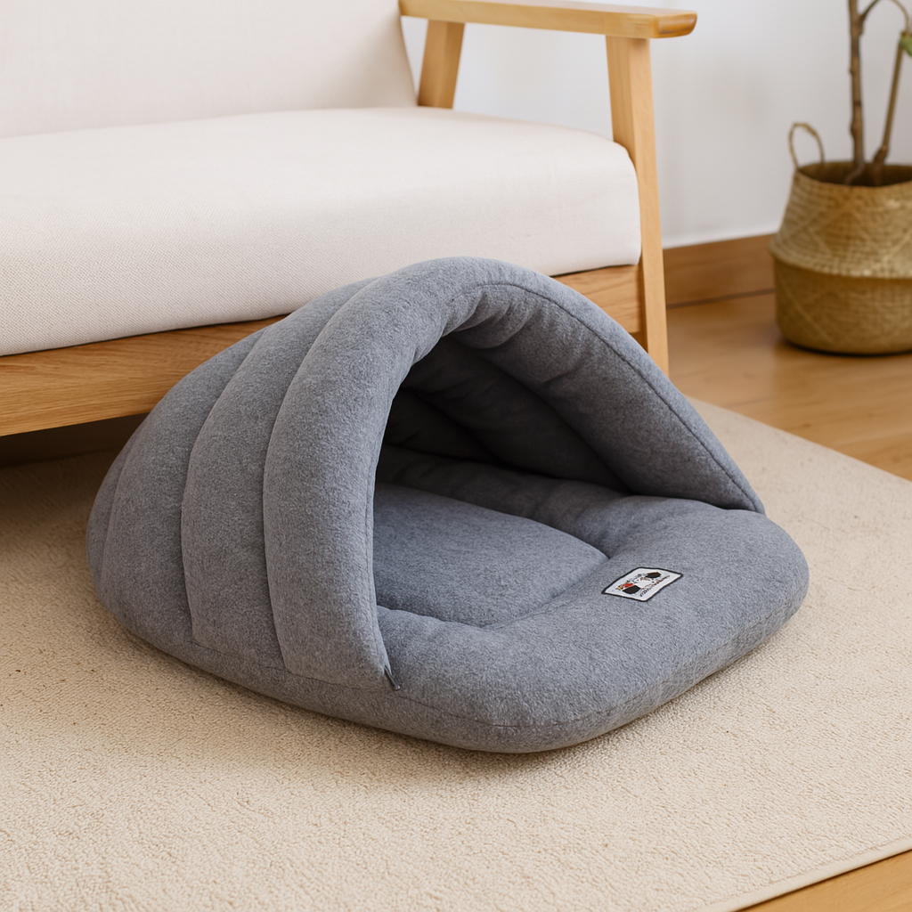 Panier chien en forme de nid pour les chiens de petites tailles. En fond il y a un canapé de couleur blanc et bois avec une plante verte sur le côté. Image produit Boutiquechien