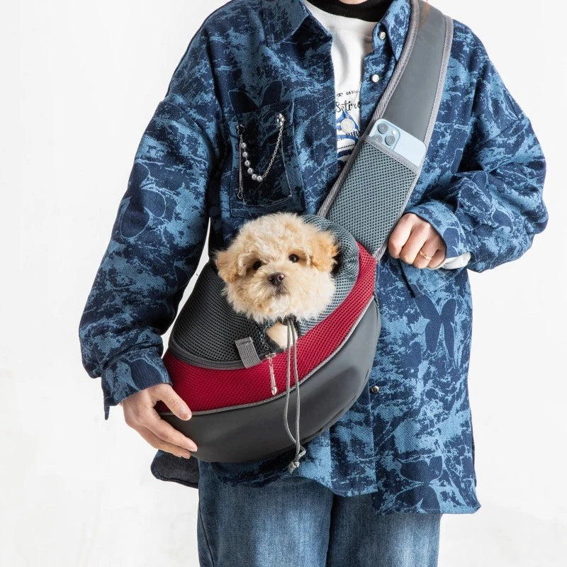 petit chien blanc est couché dans la sacoche de couleur gris et rouge. La personne est habille en bleu est possède un porte téléphone. Image produit Boutiquechien