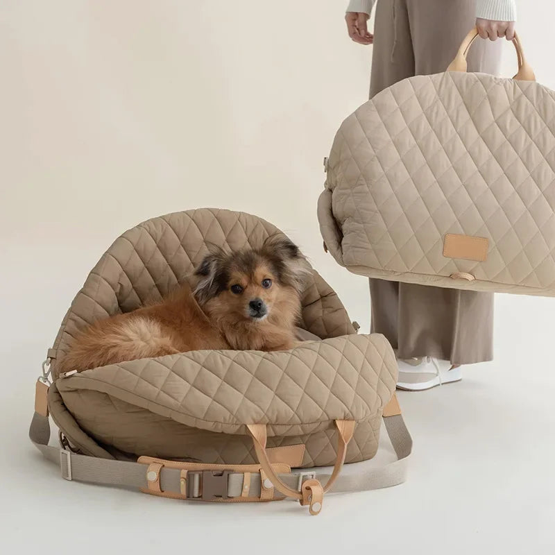 Petit chien de couleur brun a long poil dans un sac design de couleur claire. En fond une femme habillé de couleur claire avec un pantalon beige. Image produit Boutiquechien