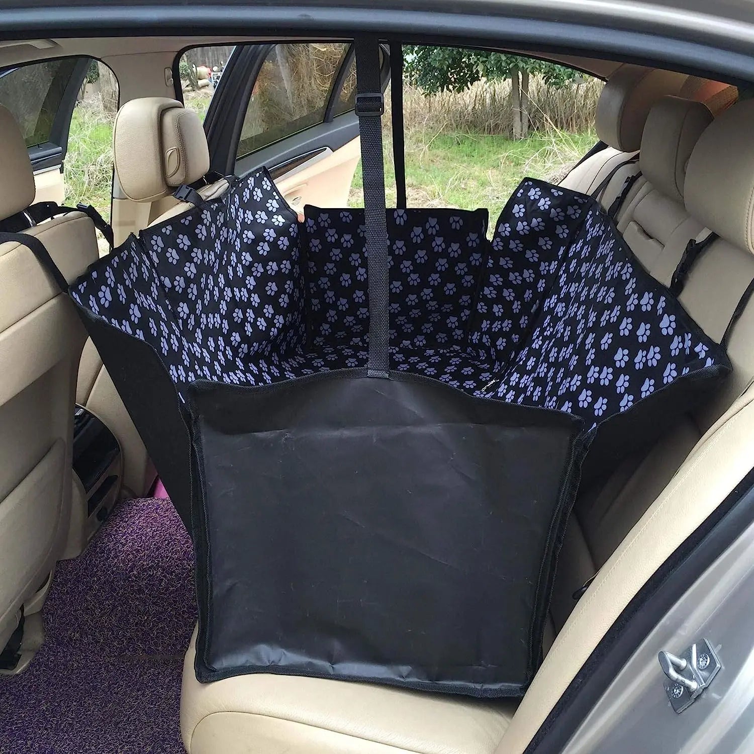 Protection de siège pour chien de couleur bleu avec des formes de pattes de couleurs blanches. Le produit est posé dans une voiture avec des sièges de couleur beige. Image produit Boutiquechien