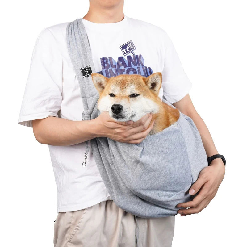 Sac pour chien gris porté par un homme habille en blanc avec un short claire. Le sac pour chien est de couleur noir avec une attache dans le sac. Image produit Boutiquechien