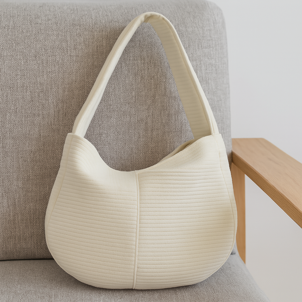 Sac de transport pour chien de couleur blanc sur un fauteuil de couleur gris. Image produit Boutiquechien