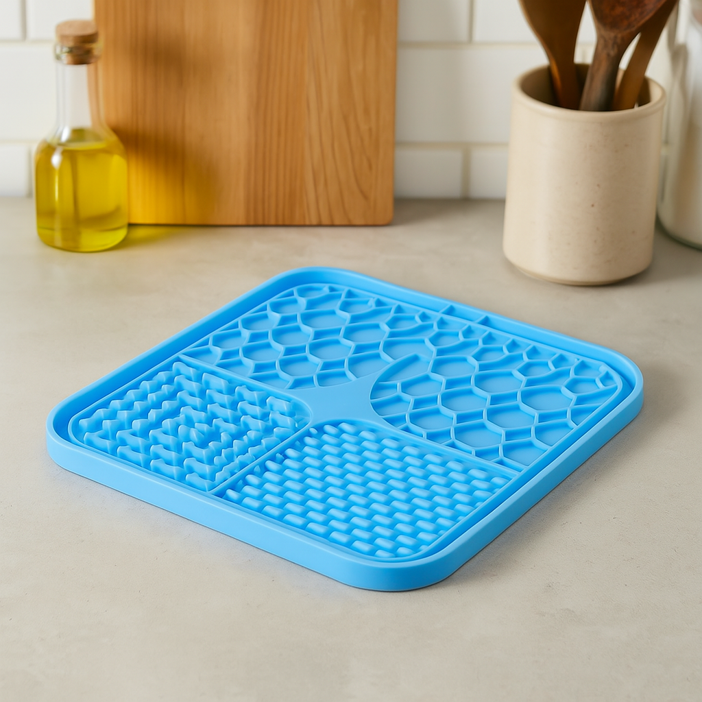 tapis chien anti glouton de couleur bleu parfait pour faire lécher votre chien. Le tapis chien est posé sur un plan de travail de couleur claire avec en fond une planche à découper en bois. Image produit Boutiquechien