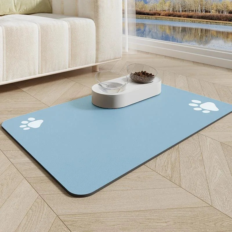 Tapis gamelle pour chien de couleur bleu avec des pattes blanche. Le tapis chien est posé dans un salon de couleur claire avec en fond un canapé blanc et un ruisseau. Image produit Boutiquechien
