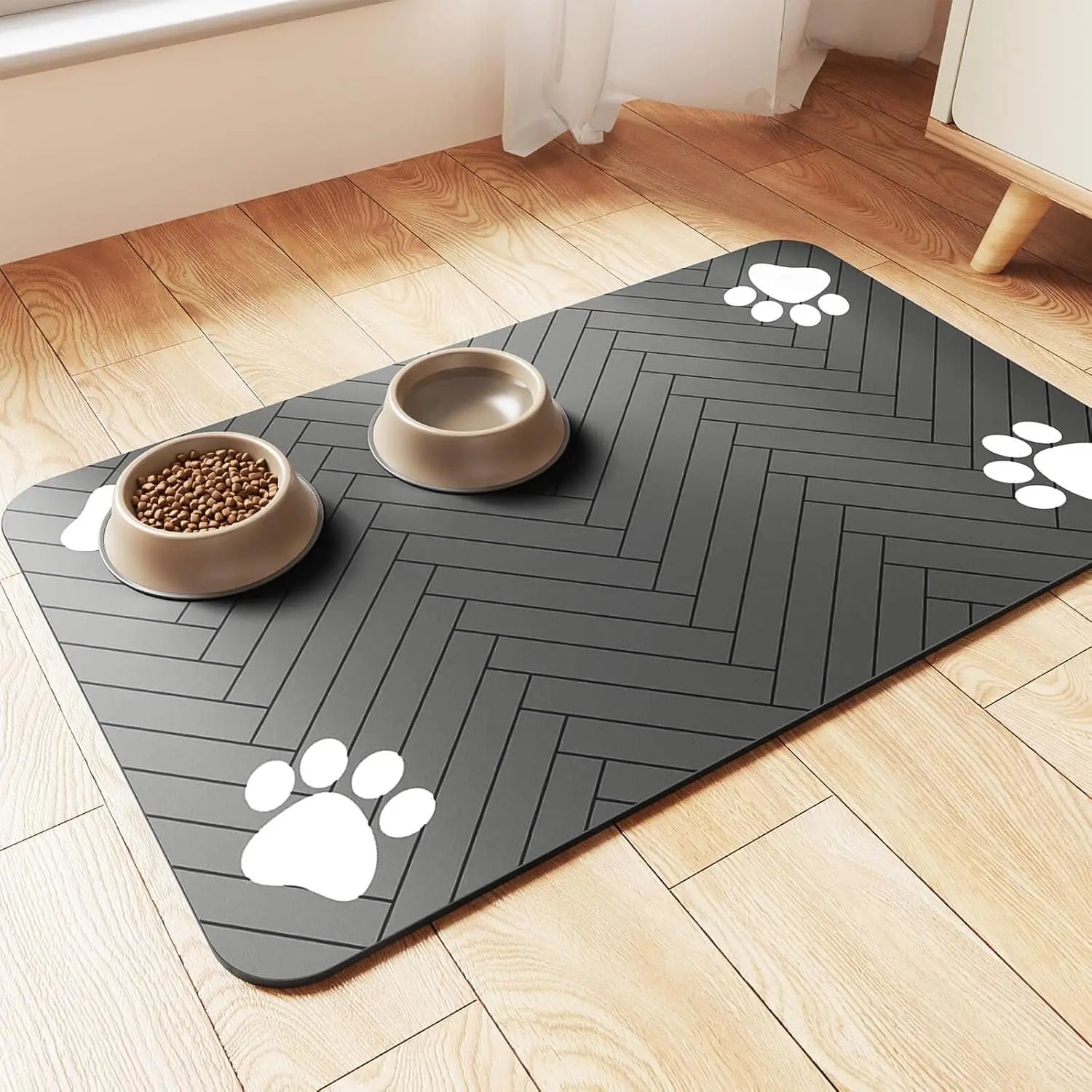Tapis gamelle pour chien de couleur noir avec des formes de pattes de couleur blanc. Le tapis chien est posé dans un salon de couleur claire avec en fond un meuble blanc. La gamelle est posé sur le tapis gamelle chien. Image produit Boutiquechien