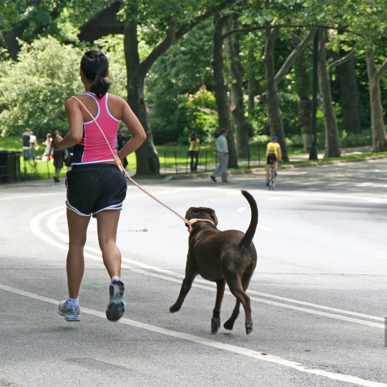 Femme courant dans la rue avec son chien de couleur foncé. Image produit Boutiquechien