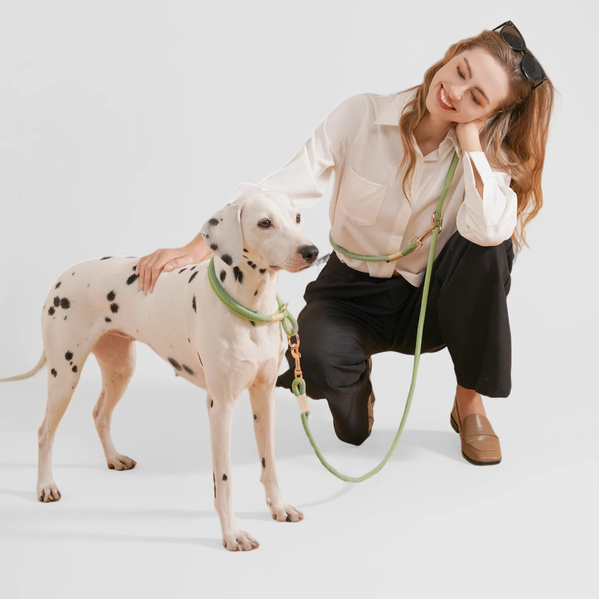femme habillé en noir et blanc avec des lunettes sur la tête accroupi a côté de son chien qui est un dalmatien de couleur blanc et noir. le chien porte un Collier chiot beagle design 