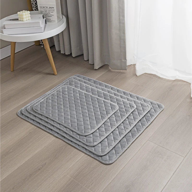 tapis lavable pour chien de couleur gris de plusieurs tailles. Le tapis pour chien est parfait pour absorber l'urine et autre. Le tapis chien est près d'une table en bois de couleur blanc. Image produit Boutiquechien