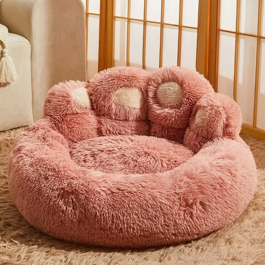 Panier chien xl en forme de pattes de couleur rose pour chien posé dans un salon de couleur claire. Un canapé blanc est posé dans le fond avec en dessous un tapis brun. Image produit Boutiquechien