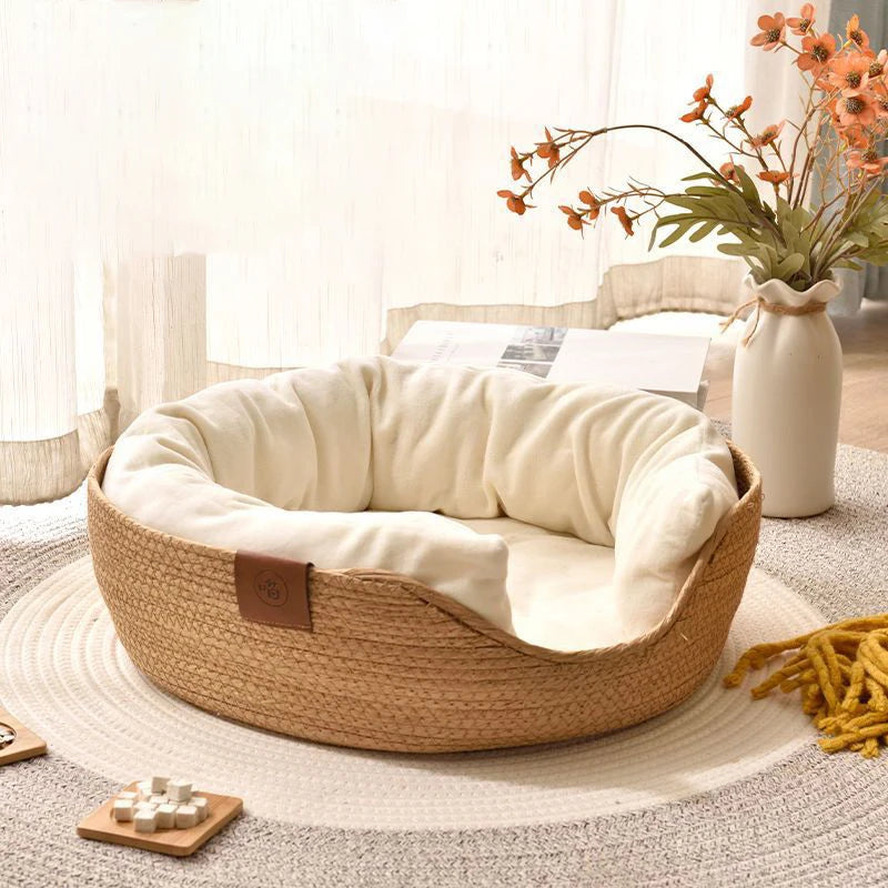 Panier pour chien en osier brun et blanc moelleux. Le panier chien est posé dans un salon de couleur claire avec sur le côté des plantes verte. Image produit Boutiquechien