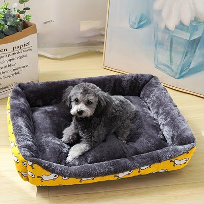 panier jaune pour chien avec des formes de canard pour chien. Le Chien est couché dans ce panier en regardant la caméra avec en fond un tableau bleu et une plante verte. Image produit boutiquechien