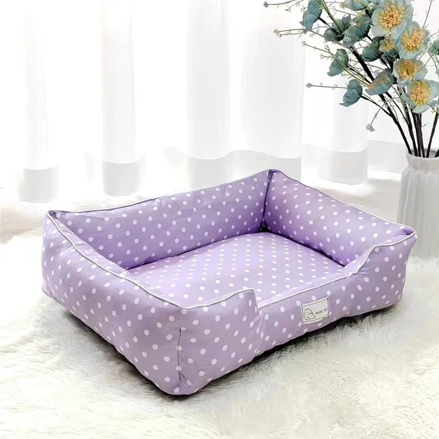 Panier pour petit chien a pois de couleur violet et blanc dans un salon de couleur blanc avec en fond une plante verte