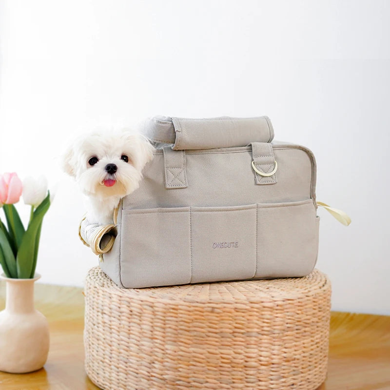 Sac pour transporter petit chien blanc sur une table en osier  Image