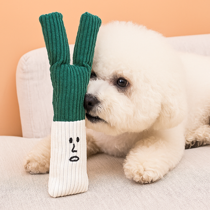 chien blanc couché sur canapé de couleur gris avec devant lui un poireau de couleur vert et blanc. Image produit Boutiquechien