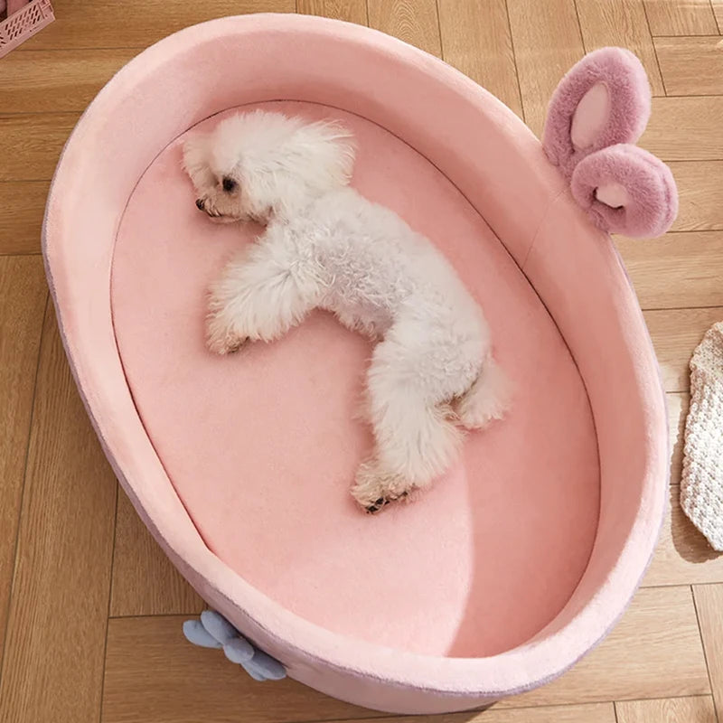 le petit chien blanc est couché dans le panier rose xl pour chine. Le panier est posé sur le sol en bois et possède des oreilles de lapin et une fleur. Image produit boutiquechien