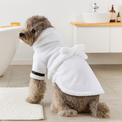 Peignoir pour chien de couleur blanc porté par un chien de taille moyenne gris. Le chien est mouillé car il est sorti de son bain qui est situé sur la gauche. Image produit Boutiquechien