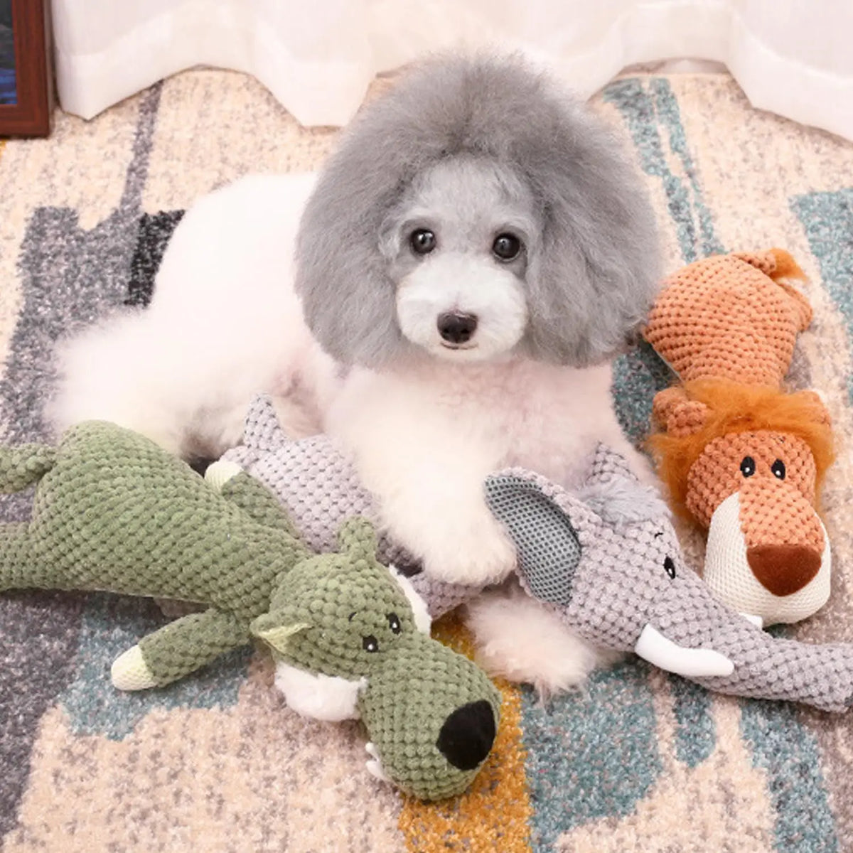 Chien blanc jouant avec ses peluche en formes d'animaux. Image produit Boutiquechien Image