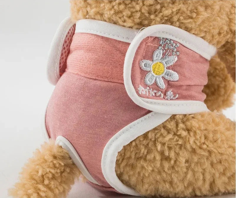 Couche pour petit chien de couleur rose et blanc sur un petit chien brun. Image produit Boutiquechien
