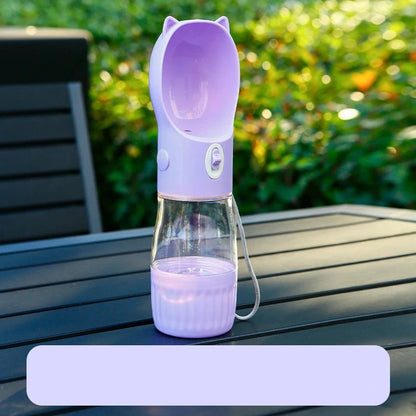 Gourde violet d'eau et nourriture posé sur une table de jardin de couleur noir avec en fond une haie verte. Image produit Boutiquechien