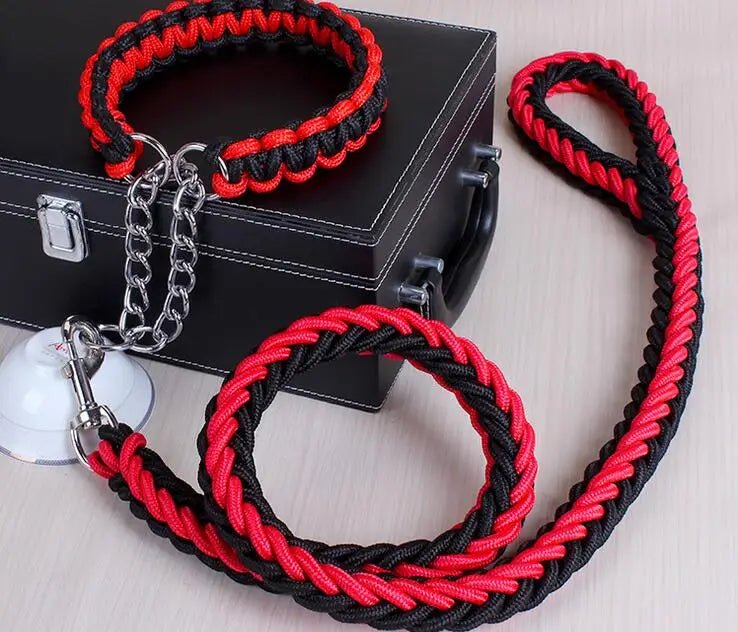 Laisse chien corde tressée de couleur rouge et noir posé sur une table claire avec en fond une boite noir