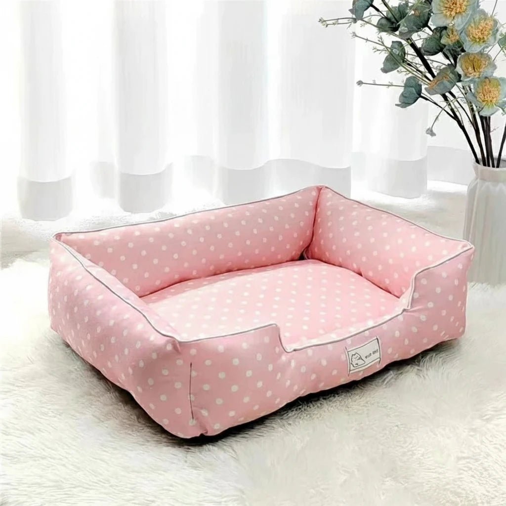 Panier pour petit chien a pois de couleur rose et blanc dans un salon de couleur claire avec en fond une plante verte