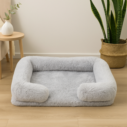 panier gris avec oreiller posé dans un petit salon. En fond il y a une plante verte et une table basse avec un pot de fleur blanc. Image produit boutiquechien
