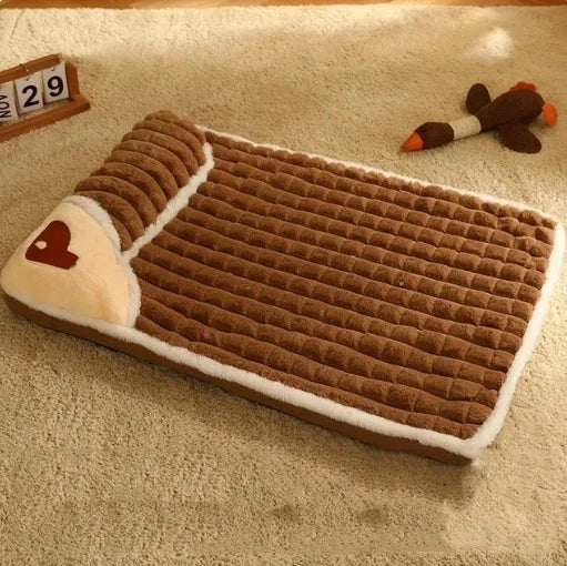 panier moelleux pour chien de couleurs brun et blanc de dimension XXL. Le panier est posé sur un grand tapis blanc sur lequel il y un jouet canard brun et un calendrier à gauche. Image produit boutiquechien