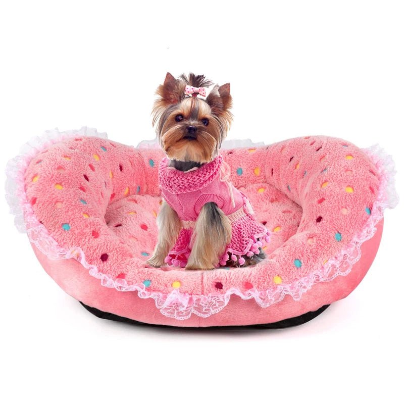 Petit chien de couleur claire avec un petit pull rose dans un petit panier rose de boutiquechien