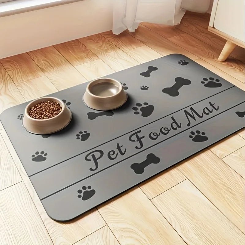 tapis gamelle pour chien de couleur gris avec des formes de pattes et d'os de couleur noir. Sur l'image il y a deux gamelle et un meuble blanc. Image produit Boutiquechien 
