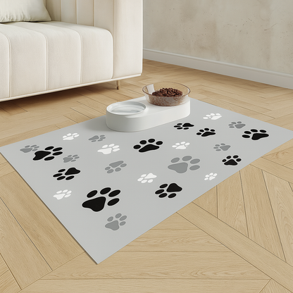 Tapis gamelle pour chien en forme de patte de couleur gris avec deux gamelles. En fond il y a un canapé de couleur blanc. Image produit Boutiquechien 